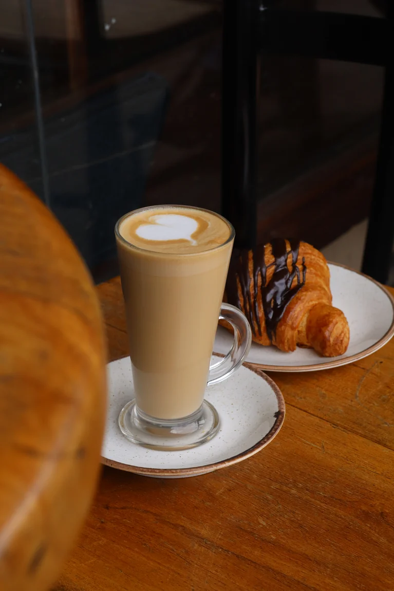 A latte served with a chocolate-drizzled croissant